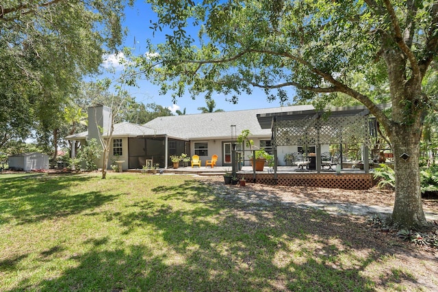 16673 75th Way N, Palm Beach Gardens, FL 33418 - back of property with a chimney, a deck, a yard, and a sunroom