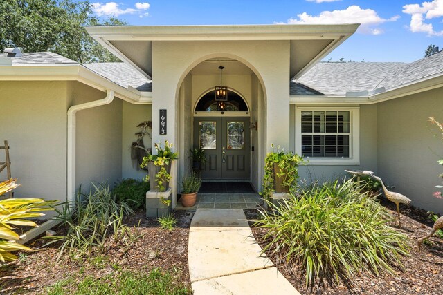 16673 75th Way N, Palm Beach Gardens, FL 33418 - view of exterior entry featuring stucco siding, a shingled roof, and french doors