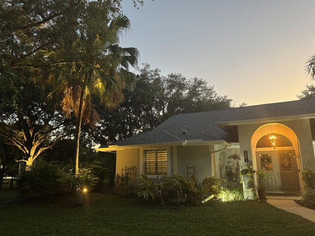 16673 75th Way N, Palm Beach Gardens, FL 33418 - view of front of house featuring stucco siding, a front yard, and a shingled roof