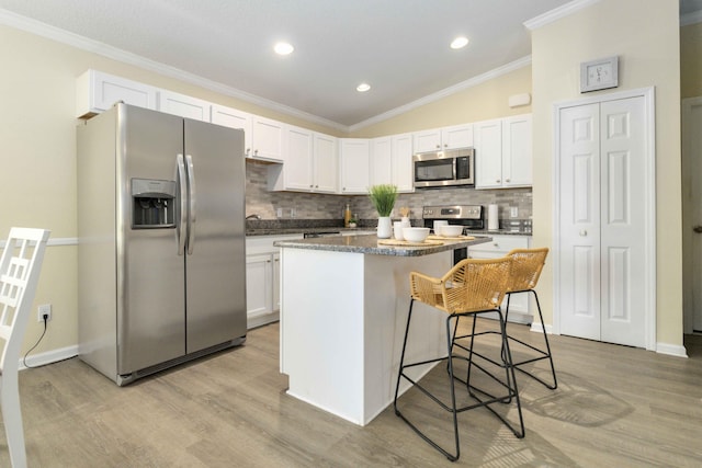 1649 Talbott St SE, Palm Bay, FL 32909 - kitchen featuring appliances with stainless steel finishes, decorative backsplash, a center island, ornamental molding, and white cabinets