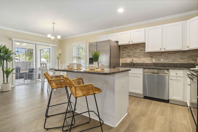 1649 Talbott St SE, Palm Bay, FL 32909 - kitchen featuring appliances with stainless steel finishes, a center island, white cabinetry, decorative backsplash, and a breakfast bar