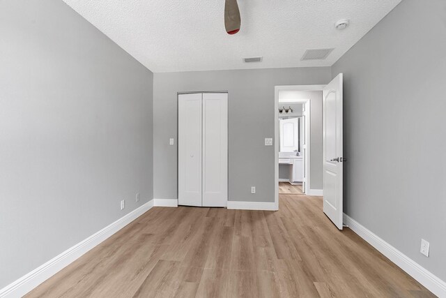 123 Canterbury Pl, Royal Palm Beach, FL 33414 - unfurnished bedroom with light wood finished floors, a textured ceiling, a closet, baseboards, and ceiling fan