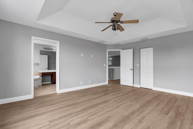 123 Canterbury Pl, Royal Palm Beach, FL 33414 - unfurnished bedroom with a raised ceiling, light wood-style floors, baseboards, ensuite bath, and a closet
