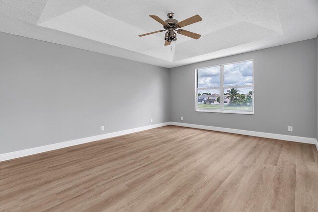 123 Canterbury Pl, Royal Palm Beach, FL 33414 - unfurnished room with a tray ceiling, light wood-style flooring, baseboards, ceiling fan, and a textured ceiling