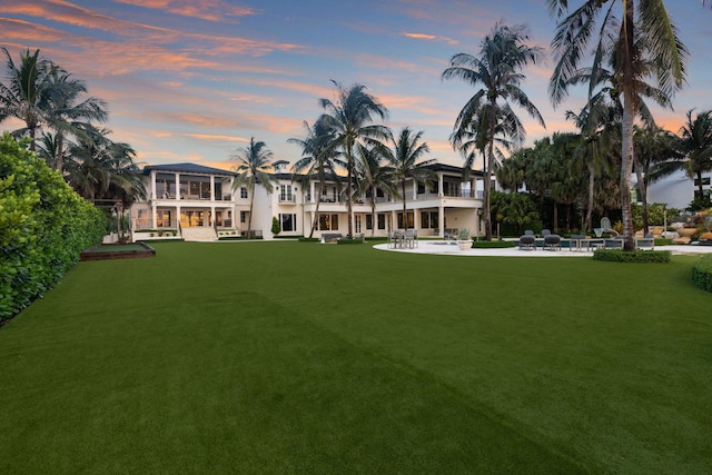 526 N Ocean Blvd, Delray Beach, FL 33483 - back of house at dusk with a balcony, a patio area, a yard, and stucco siding