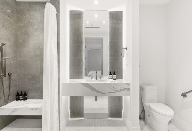 526 N Ocean Blvd, Delray Beach, FL 33483 - bathroom featuring a tile shower, toilet, baseboards, and a sink
