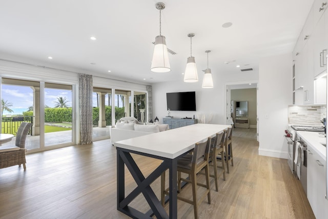 526 N Ocean Blvd, Delray Beach, FL 33483 - kitchen with white cabinetry, backsplash, light countertops, light wood-style floors, and hanging light fixtures