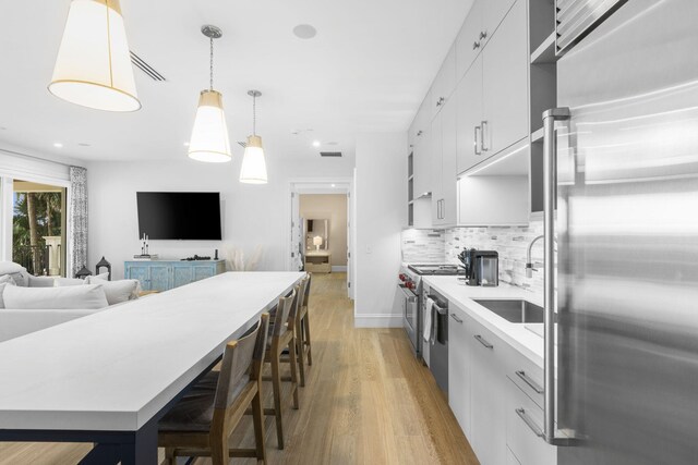 526 N Ocean Blvd, Delray Beach, FL 33483 - kitchen featuring premium appliances, a sink, light wood-type flooring, white cabinets, and tasteful backsplash