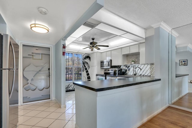 1858 SW Palm City Rd Unit 205, Stuart, FL 34994 - kitchen with stainless steel appliances, dark countertops, a peninsula, a ceiling fan, and a textured ceiling