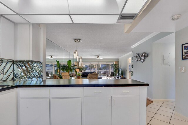 1858 SW Palm City Rd Unit 205, Stuart, FL 34994 - kitchen with dark countertops, light tile patterned flooring, white cabinets, a peninsula, and a ceiling fan