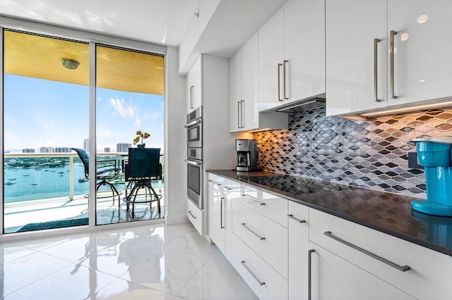 2640 Lake Shore Dr Unit 2307, Riviera Beach, FL 33404 - kitchen with dark countertops, light marble finish flooring, backsplash, white cabinets, and expansive windows