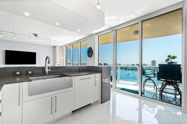 2640 Lake Shore Dr Unit 2307, Riviera Beach, FL 33404 - kitchen with a sink, dark countertops, a wall of windows, white cabinets, and a water view