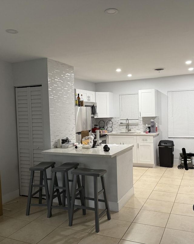 3600 Jackson St Unit 22, Hollywood, FL 33021 - kitchen featuring a sink, a peninsula, decorative backsplash, white cabinets, and light tile patterned floors