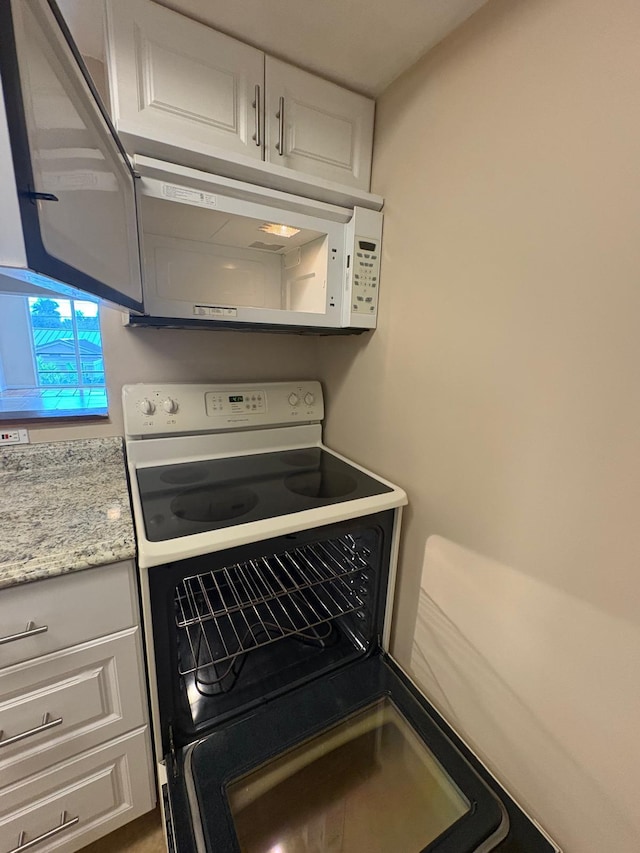 118 Yacht Club Dr Unit 7, North Palm Beach, FL 33408 - kitchen with white microwave, range with electric stovetop, and white cabinetry