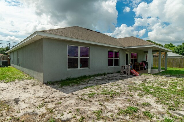 517 SW Cherryhill Rd, Port Saint Lucie, FL 34953 - rear view of property featuring central air condition unit, stucco siding, a patio, and roof with shingles