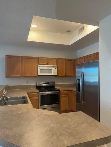10280 SW Stephanie Way Unit 8209, Port Saint Lucie, FL 34987 - kitchen featuring appliances with stainless steel finishes, a sink, a peninsula, a tray ceiling, and recessed lighting