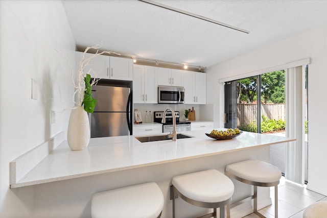 744 Buttonwood Ln Unit 411-D, Boynton Beach, FL 33436 - kitchen featuring appliances with stainless steel finishes, a peninsula, a kitchen bar, white cabinetry, and track lighting