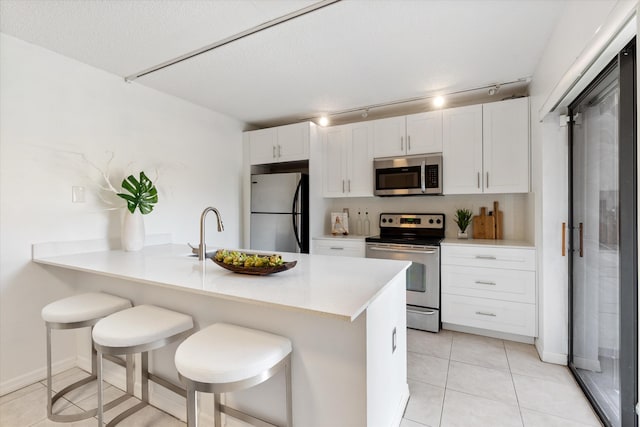 744 Buttonwood Ln Unit 411-D, Boynton Beach, FL 33436 - kitchen featuring appliances with stainless steel finishes, track lighting, light countertops, a sink, and white cabinetry