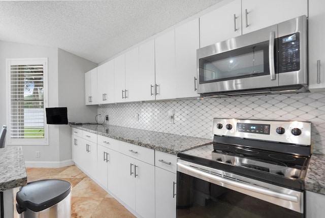 7216 Copperfield Cir, Lake Worth, FL 33467 - kitchen featuring appliances with stainless steel finishes, backsplash, lofted ceiling, white cabinets, and light stone countertops