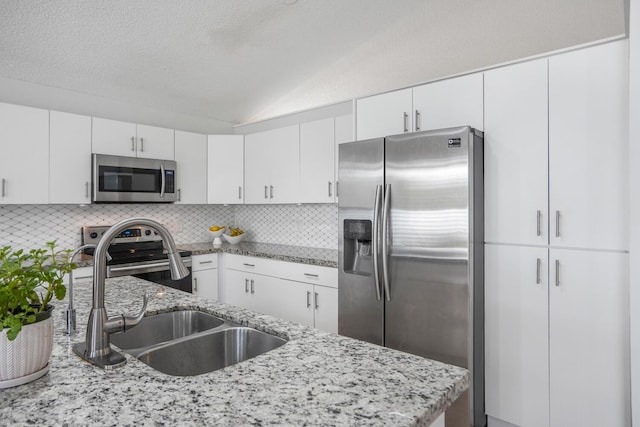 7216 Copperfield Cir, Lake Worth, FL 33467 - kitchen with stainless steel appliances, a sink, lofted ceiling, decorative backsplash, and white cabinets