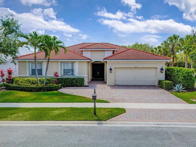 101 Sedona Way, Palm Beach Gardens, FL 33418 - mediterranean / spanish-style home with driveway, an attached garage, a tiled roof, a front lawn, and stucco siding