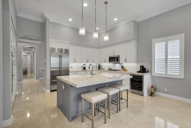 101 Sedona Way, Palm Beach Gardens, FL 33418 - kitchen with appliances with stainless steel finishes, beverage cooler, a sink, a high ceiling, and arched walkways