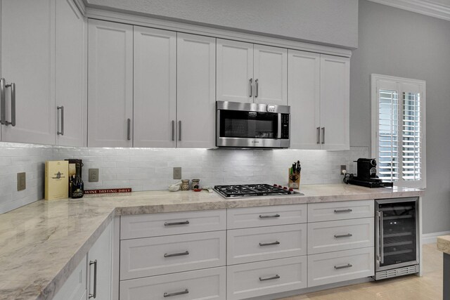 101 Sedona Way, Palm Beach Gardens, FL 33418 - kitchen featuring beverage cooler, appliances with stainless steel finishes, decorative backsplash, white cabinetry, and crown molding