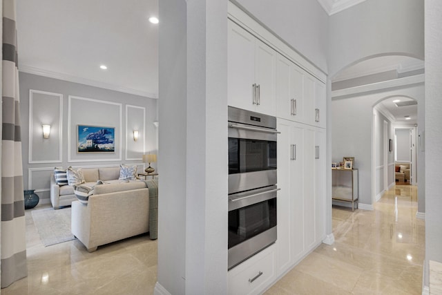 101 Sedona Way, Palm Beach Gardens, FL 33418 - kitchen with stainless steel double oven, arched walkways, crown molding, light marble finish flooring, and white cabinetry