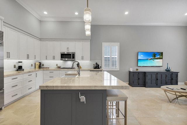101 Sedona Way, Palm Beach Gardens, FL 33418 - kitchen with ornamental molding, stainless steel microwave, a sink, white cabinetry, and backsplash