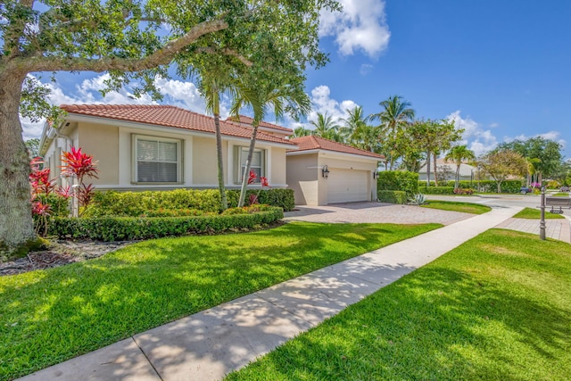 101 Sedona Way, Palm Beach Gardens, FL 33418 - mediterranean / spanish house featuring a garage, a tiled roof, stucco siding, decorative driveway, and a front yard