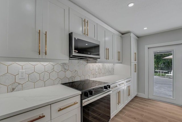 18228 48th Ave N, The Acreage, FL 33470 - kitchen featuring stainless steel microwave, range with electric cooktop, white cabinetry, light wood-style flooring, and tasteful backsplash