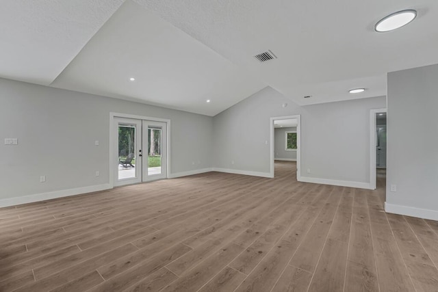18228 48th Ave N, The Acreage, FL 33470 - unfurnished living room featuring french doors, light wood-style floors, baseboards, and lofted ceiling