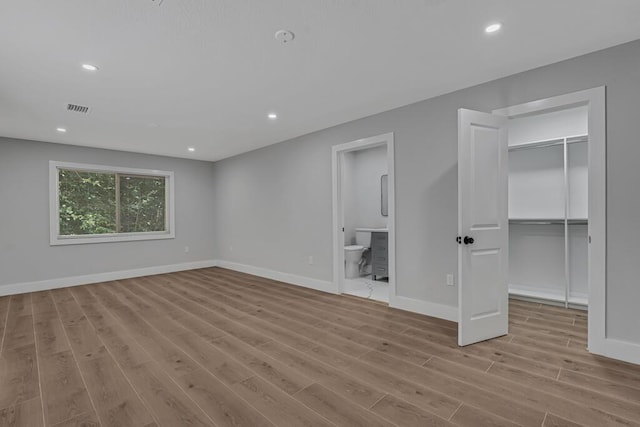 18228 48th Ave N, The Acreage, FL 33470 - unfurnished bedroom with wood finished floors, a walk in closet, baseboards, ensuite bath, and recessed lighting