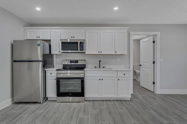 18228 48th Ave N, The Acreage, FL 33470 - kitchen with appliances with stainless steel finishes, a sink, light countertops, baseboards, and white cabinets