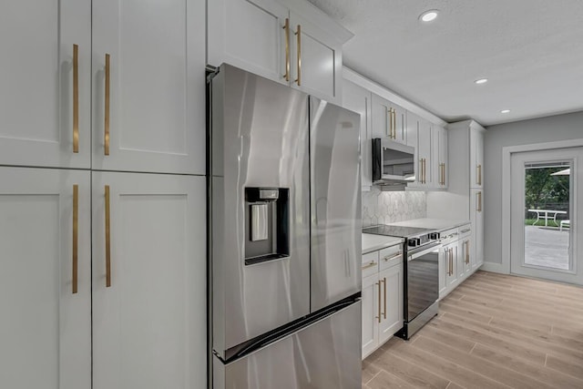 18228 48th Ave N, The Acreage, FL 33470 - kitchen featuring stainless steel appliances, light wood-style flooring, light countertops, tasteful backsplash, and white cabinetry