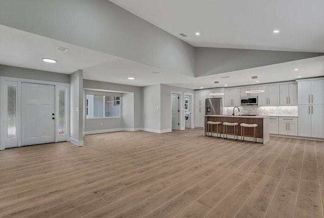 18228 48th Ave N, The Acreage, FL 33470 - unfurnished living room featuring a sink, recessed lighting, light wood-style flooring, baseboards, and high vaulted ceiling