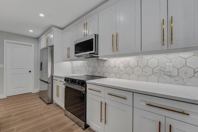18228 48th Ave N, The Acreage, FL 33470 - kitchen with range with electric cooktop, stainless steel fridge, light wood finished floors, light countertops, and white cabinetry