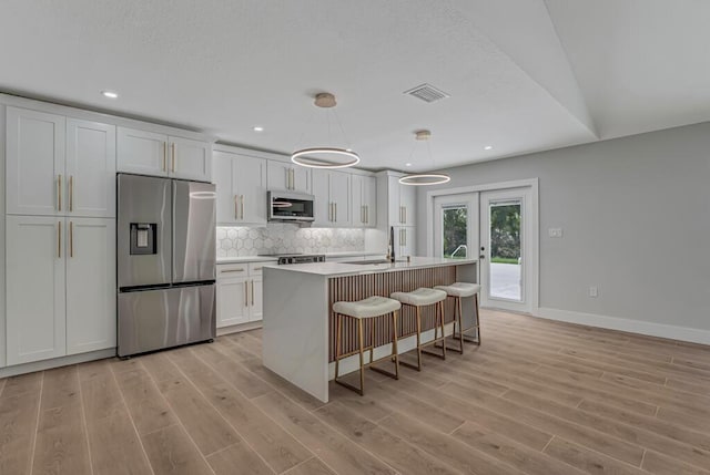 18228 48th Ave N, The Acreage, FL 33470 - kitchen with stainless steel appliances, light wood-style floors, white cabinets, decorative backsplash, and recessed lighting