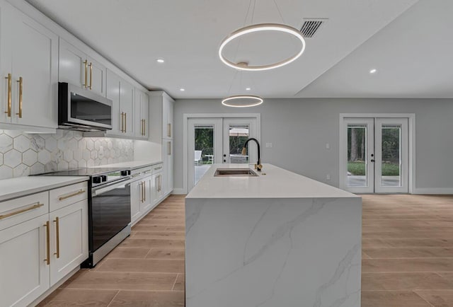 18228 48th Ave N, The Acreage, FL 33470 - kitchen with french doors, appliances with stainless steel finishes, a sink, decorative backsplash, and light wood-style flooring
