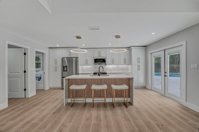18228 48th Ave N, The Acreage, FL 33470 - kitchen featuring appliances with stainless steel finishes, light wood-style floors, washer / clothes dryer, an island with sink, and recessed lighting