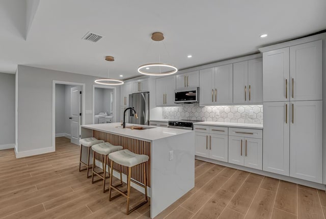 18228 48th Ave N, The Acreage, FL 33470 - kitchen with stainless steel appliances, light wood-style flooring, light countertops, baseboards, and a kitchen island with sink