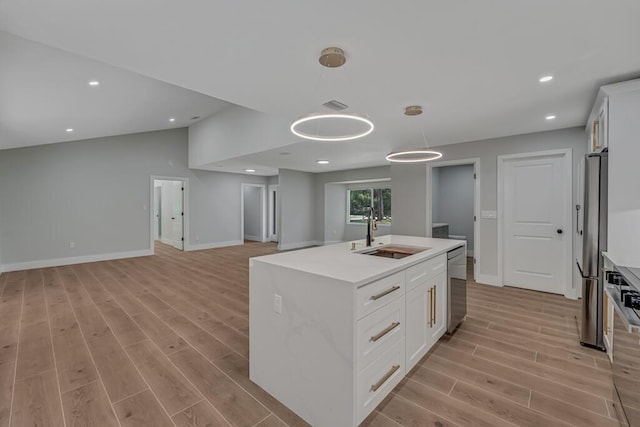 18228 48th Ave N, The Acreage, FL 33470 - kitchen featuring a sink, light wood-style floors, appliances with stainless steel finishes, decorative light fixtures, and a center island with sink