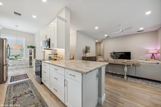 5096 SE Sweetbrier Ter, Hobe Sound, FL 33455 - kitchen with stainless steel appliances, light stone counters, white cabinetry, open floor plan, and light wood-type flooring