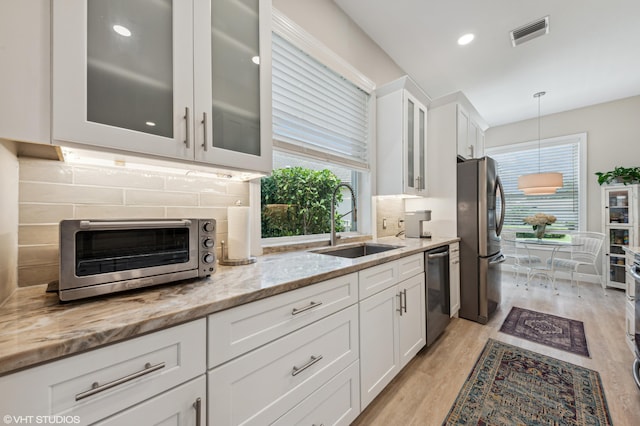 5096 SE Sweetbrier Ter, Hobe Sound, FL 33455 - kitchen featuring appliances with stainless steel finishes, a sink, tasteful backsplash, light wood finished floors, and light stone countertops
