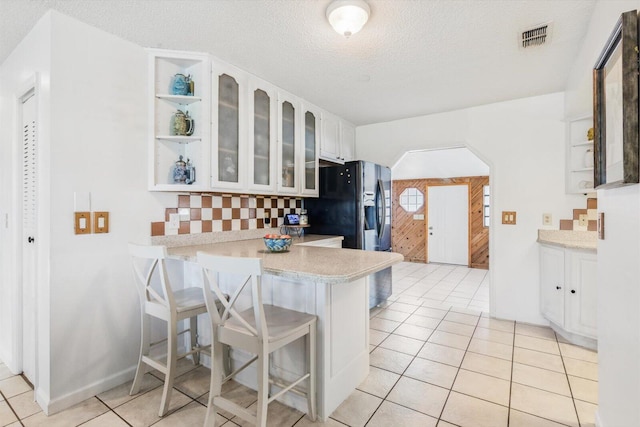 1430 SE Ocean Ln, Port Saint Lucie, FL 34983 - kitchen featuring open shelves, a peninsula, a kitchen breakfast bar, white cabinetry, and a textured ceiling