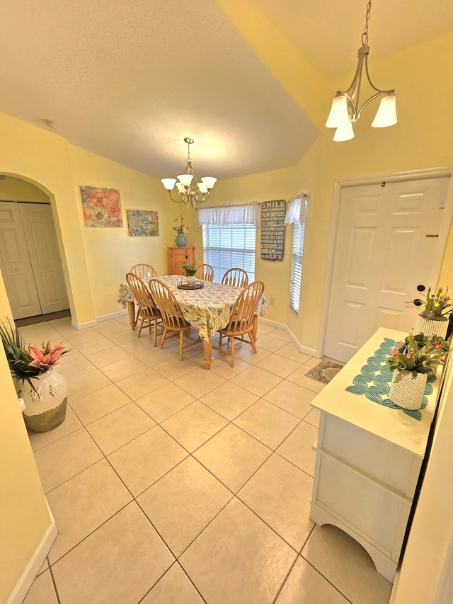 5237 NW Milner Dr, Port Saint Lucie, FL 34983 - dining room featuring a chandelier, light tile patterned floors, arched walkways, baseboards, and vaulted ceiling