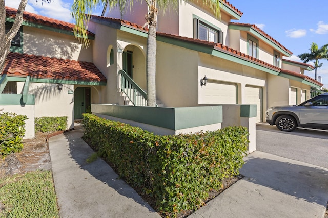 23 Lexington Ln W Unit A, Palm Beach Gardens, FL 33418 - view of property exterior featuring an attached garage, a tile roof, asphalt driveway, and stucco siding