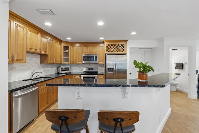 23 Lexington Ln W Unit A, Palm Beach Gardens, FL 33418 - kitchen featuring stainless steel appliances, a sink, tasteful backsplash, a kitchen bar, and light wood-style floors