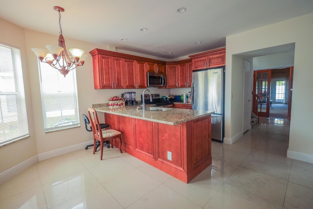 1356 N Climbing Rose, West Palm Beach, FL 33415 - kitchen with stainless steel appliances, reddish brown cabinets, a sink, a chandelier, and a peninsula