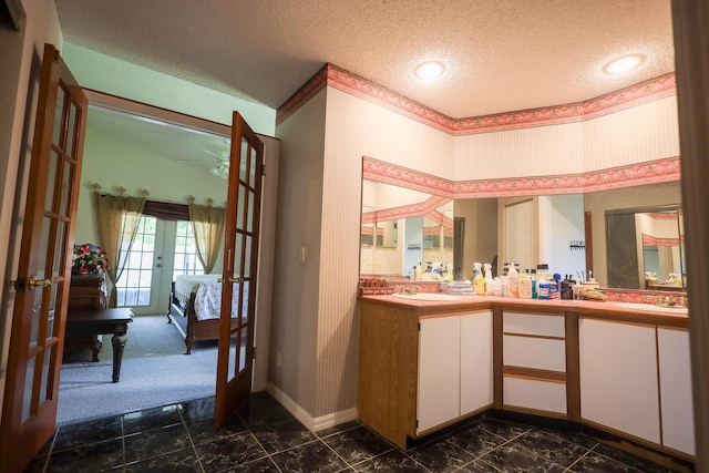 1356 N Climbing Rose, West Palm Beach, FL 33415 - ensuite bathroom with french doors, double vanity, a textured ceiling, baseboards, and ornamental molding